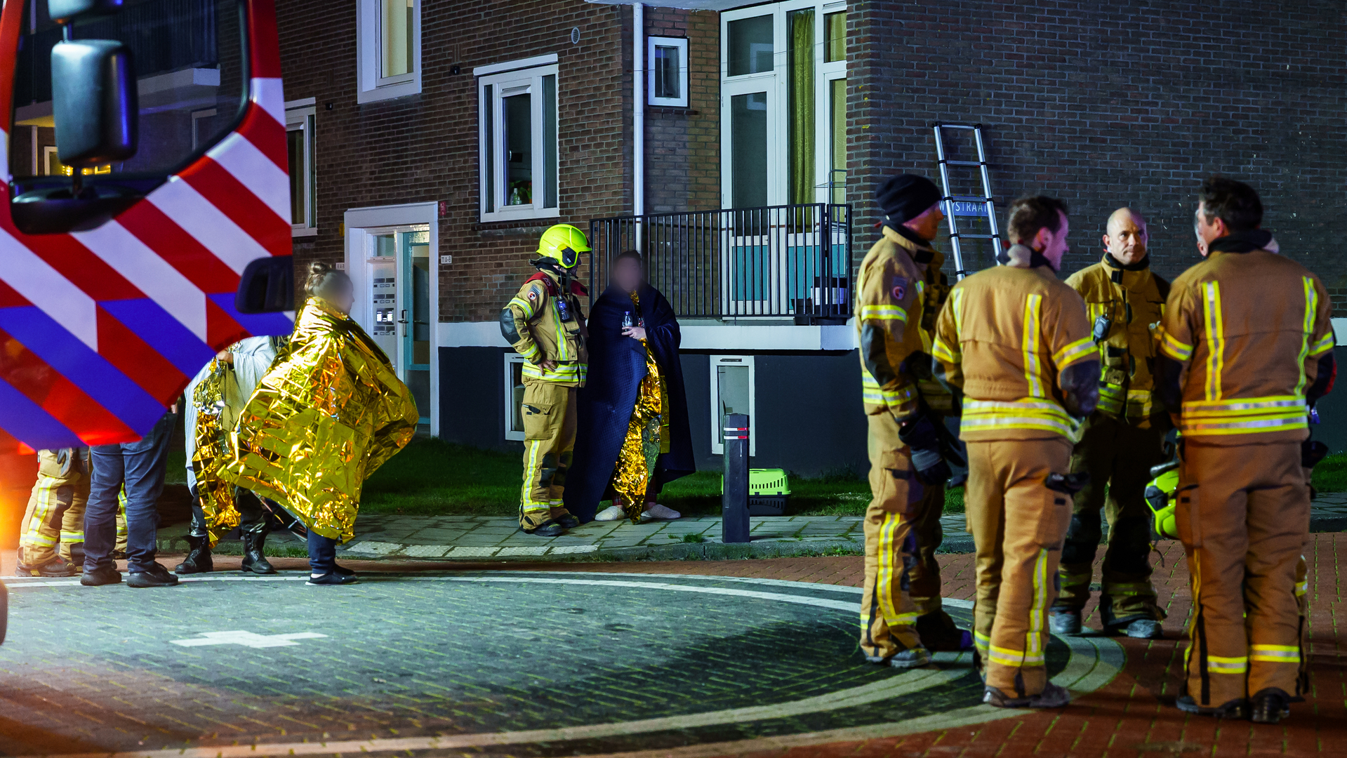 Bewoners staan gewikkeld in warmtedekens op straat