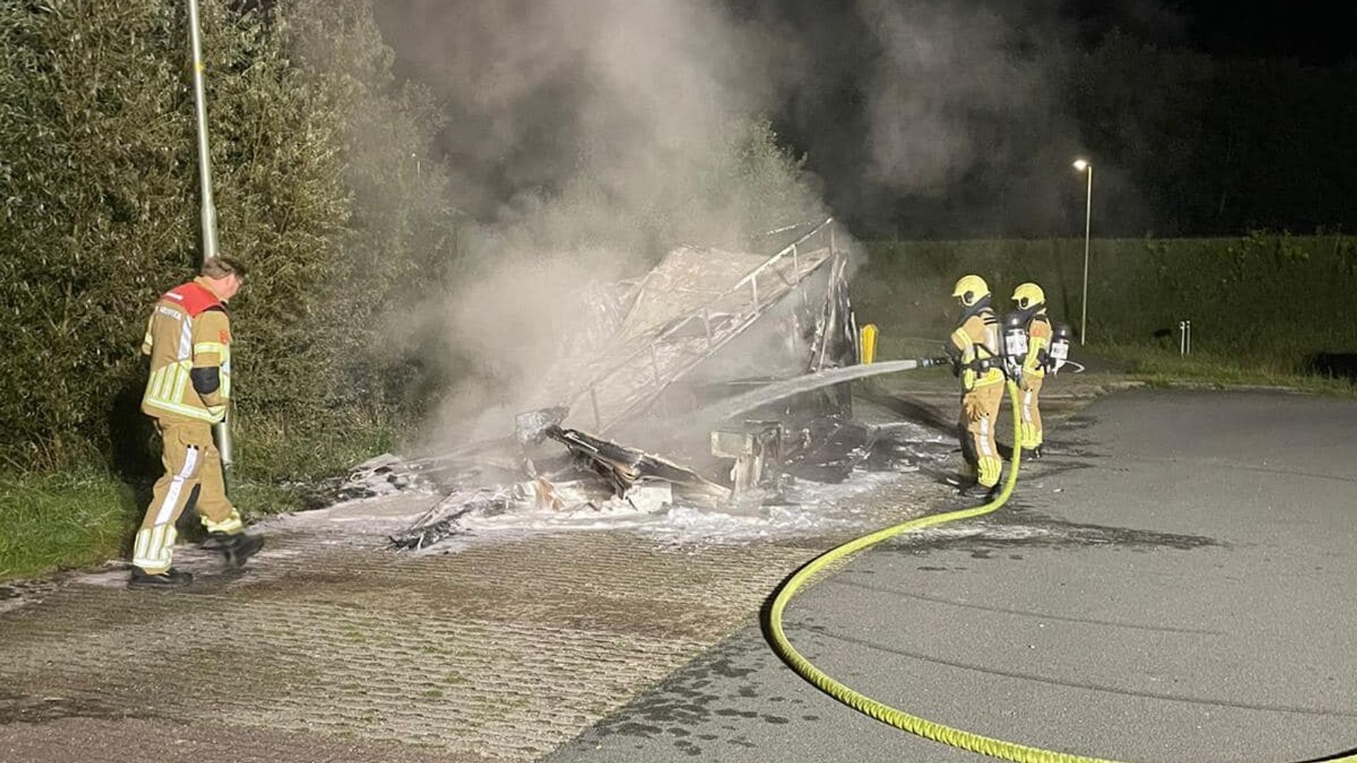Brandweer bij de uitgebrande wagen