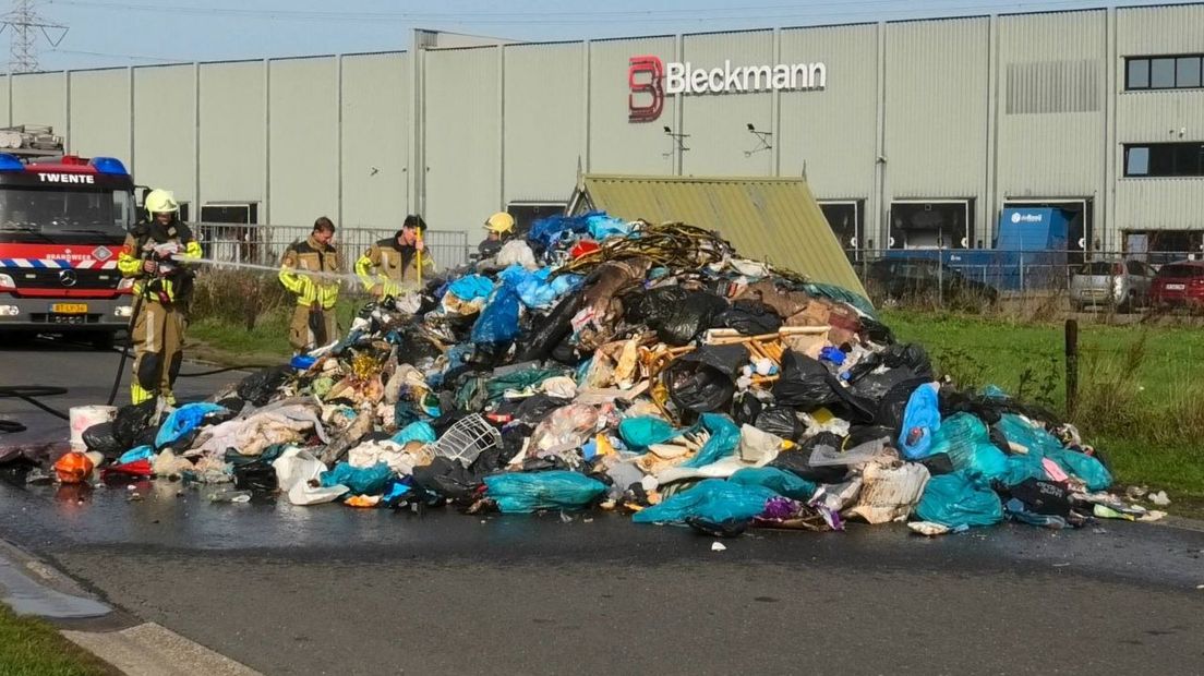 Brandweer blust het over straat verspreide afval in Enschede