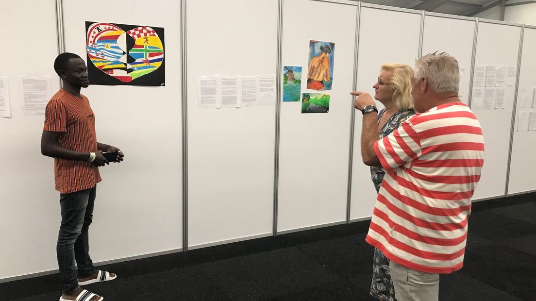 De bewoner van de opvang met vrijwilliger Ron Meinema en wethouder Wil Kosterman naast een kunstwerk dat hij maakte