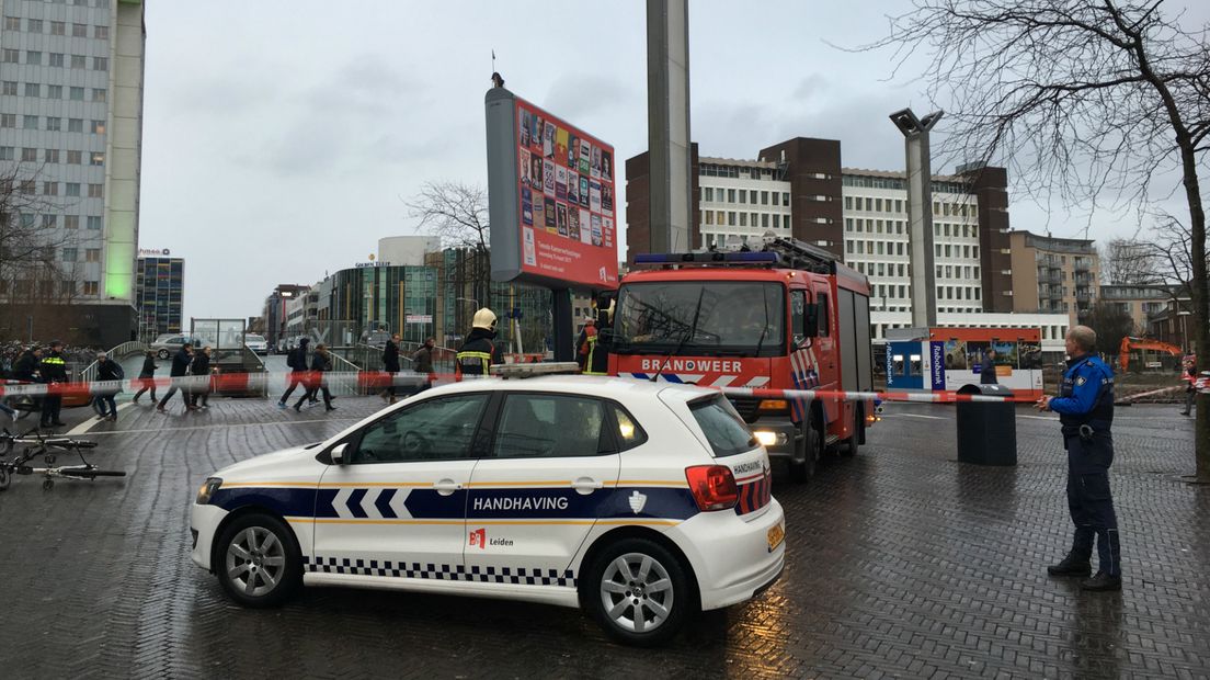 De brandweer ontfermt zich over het losgeraakte verkiezingsbord bij station Leiden Centraal. 