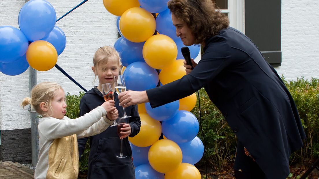 Madelon Flint, voorzitter van Stichting Ronald McDonald Huis Utrecht, knipt samen met twee jonge gasten het lintje door.