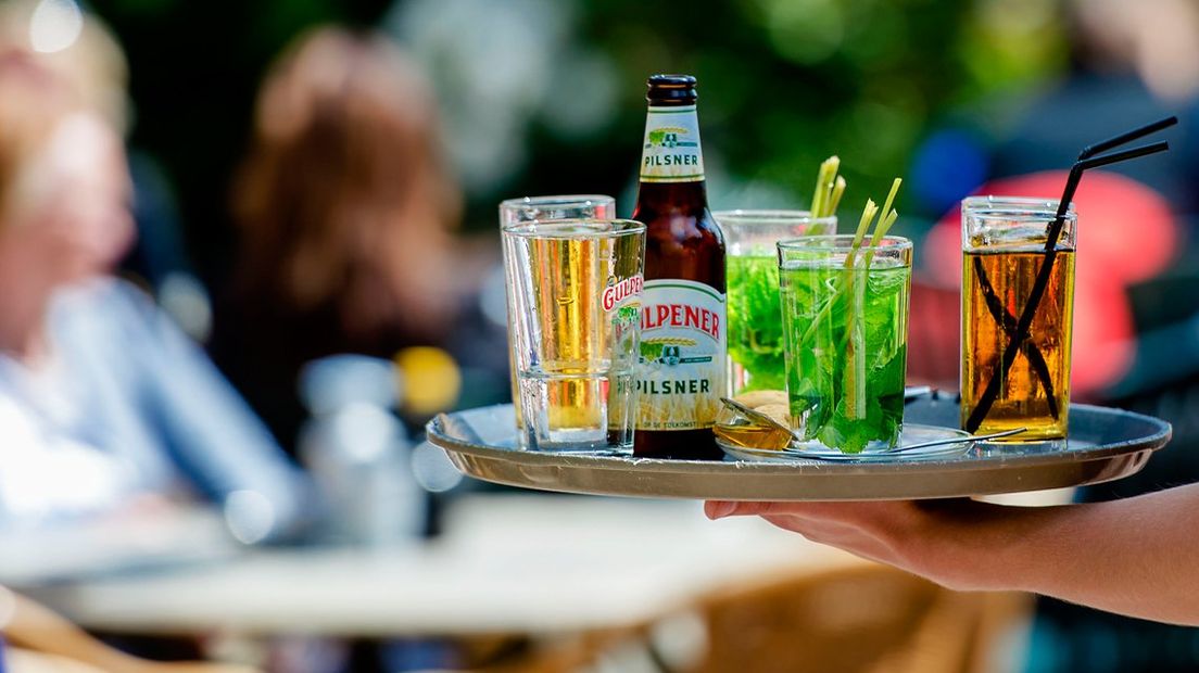 Een ober komt een drankje brengen op het terras.