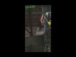 Drie aanhangers van Fenerbache gooien een paal met een betonnen tegel over het hek.