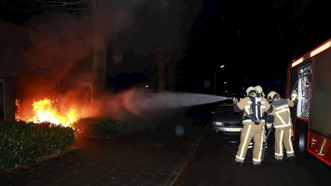 Brandweerlieden blussen de containerbrand