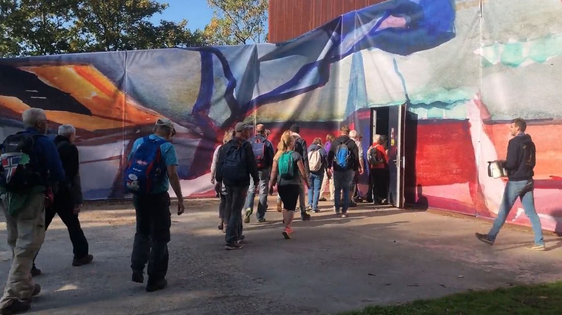 Wandelaars lopen door een levensgroot schilderij tijdens Tocht om de Noord 2018