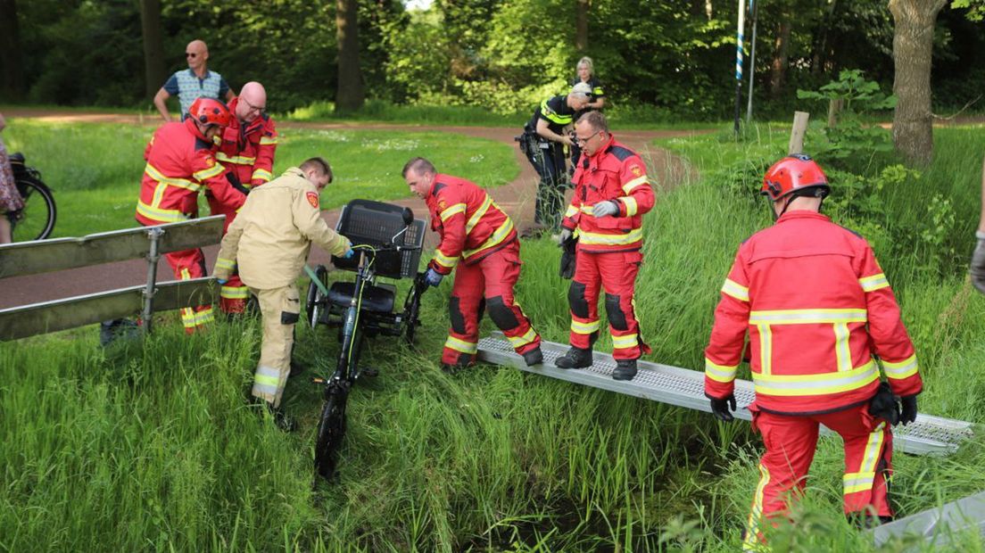 Brandweermannen trekken de driewieler op de wal