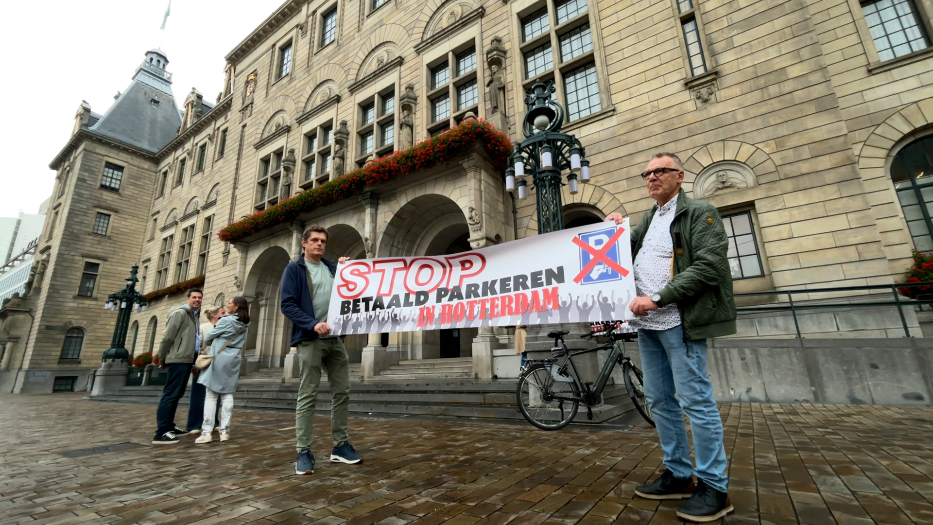 Een twintigtal personen staan voor het stadhuis om te demonstreren