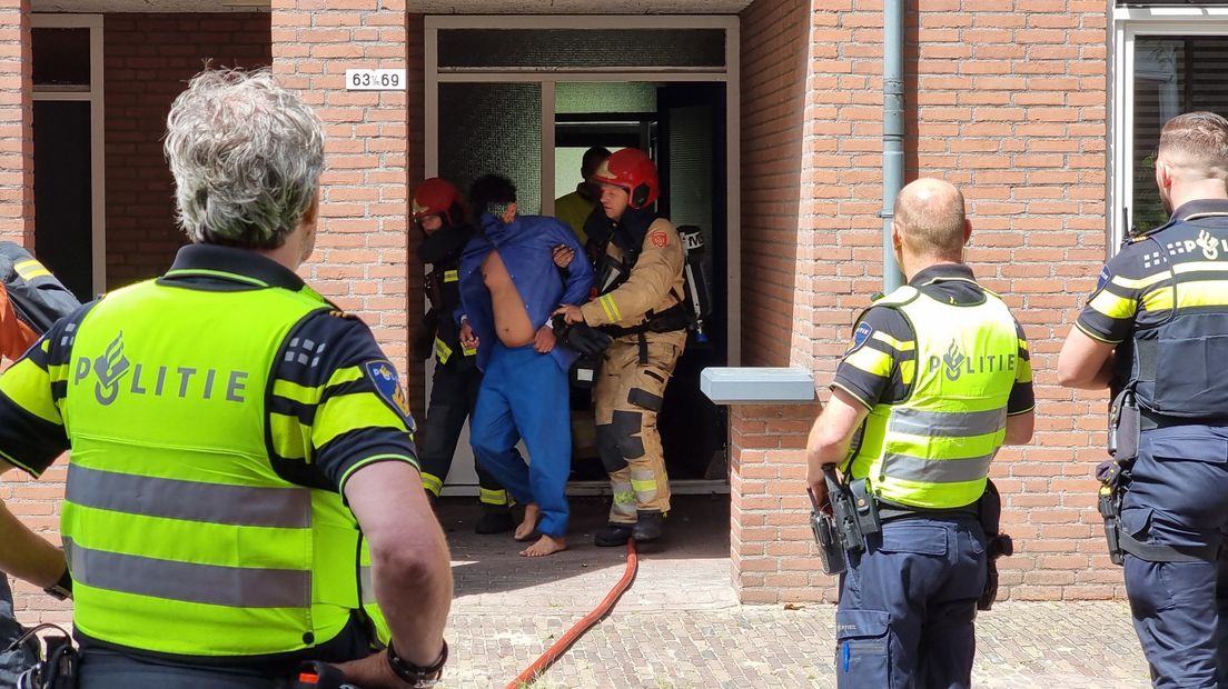 Brandweermannen redden een persoon uit de brandende woning