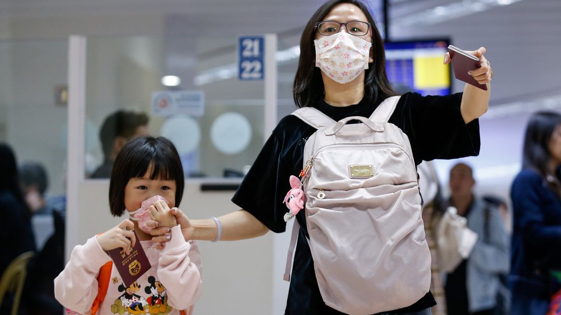Een vrouw met haar kind gaan China uit vanwege het coronavirus