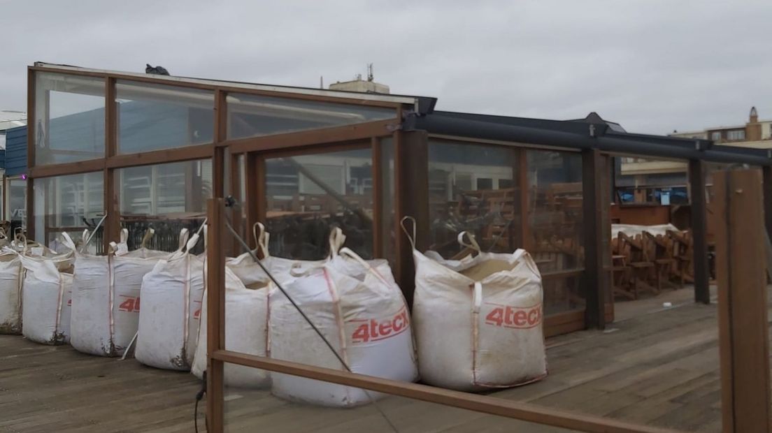 Strandtent Werelds met zandzakken voor de deur.