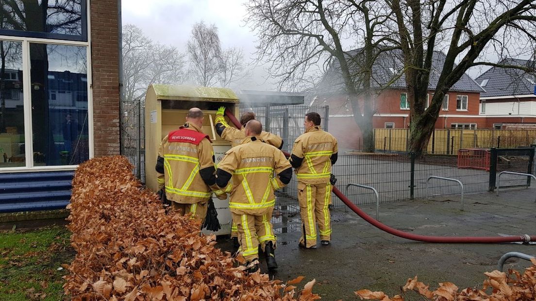 Brandweer dooft vlammen in kledingcontainer