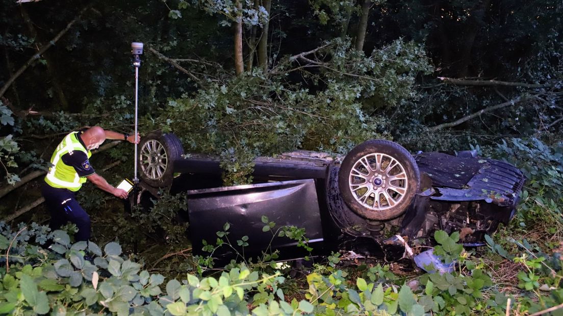 De politie doet onderzoek bij de gekantelde auto in Wamel.