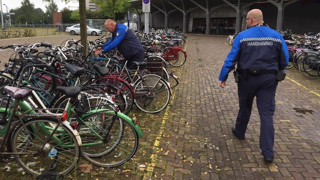 Toezichthouder Plomp (r) en zijn collega bevestigen waarschuwingsbriefjes