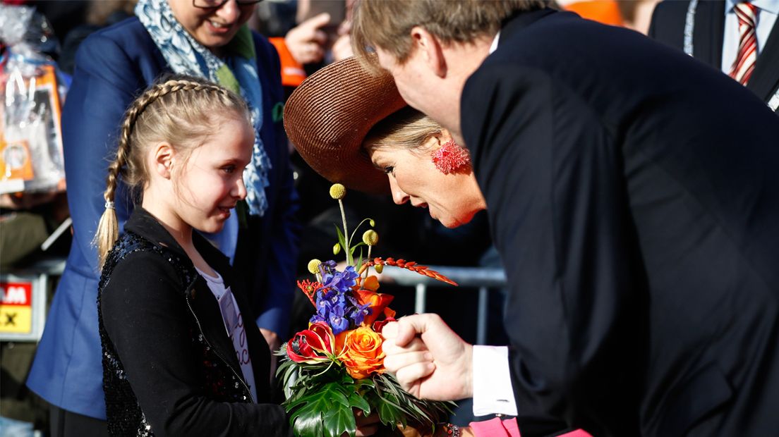 Het koningspaar neemt een bloemetje in ontvangst tijdens hun bezoek aan de gemeente Krimpenerwaard