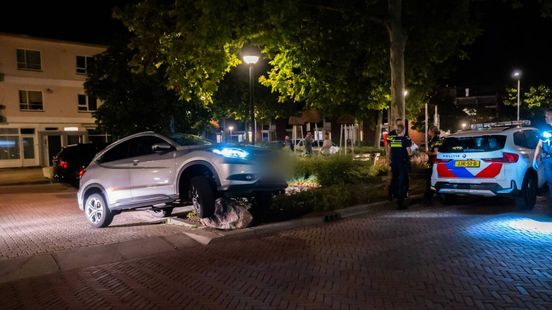 Vluchtende automobilist strandt met auto bovenop grote kei
