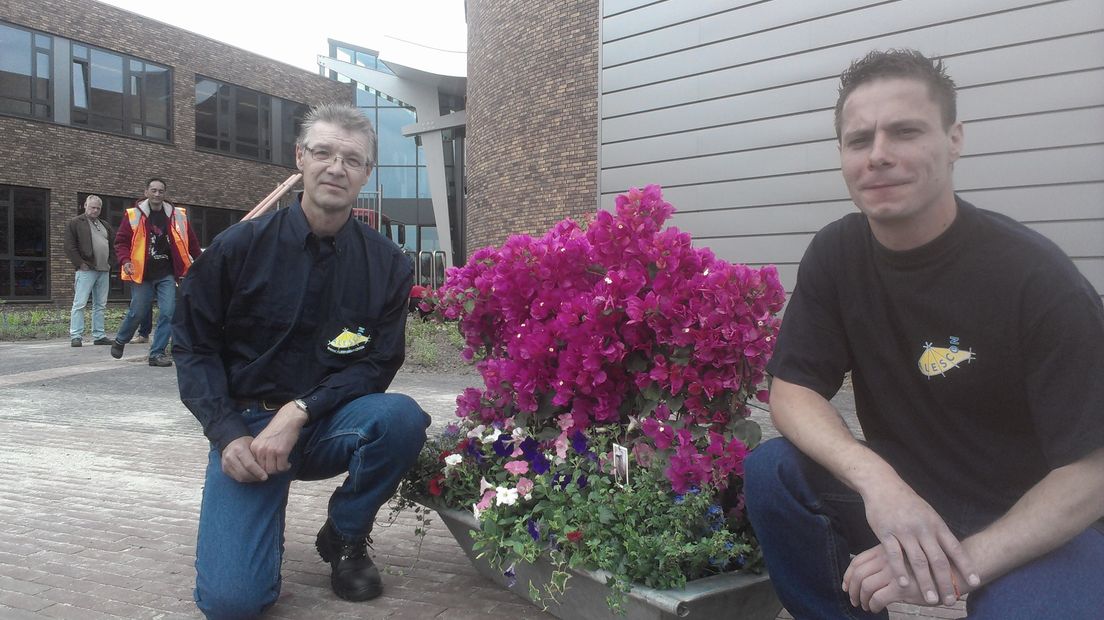 Alescon-medewerkers Erik Gaasbeek en Gezienus Kühl bieden stuk dakgoot met bloemen aan