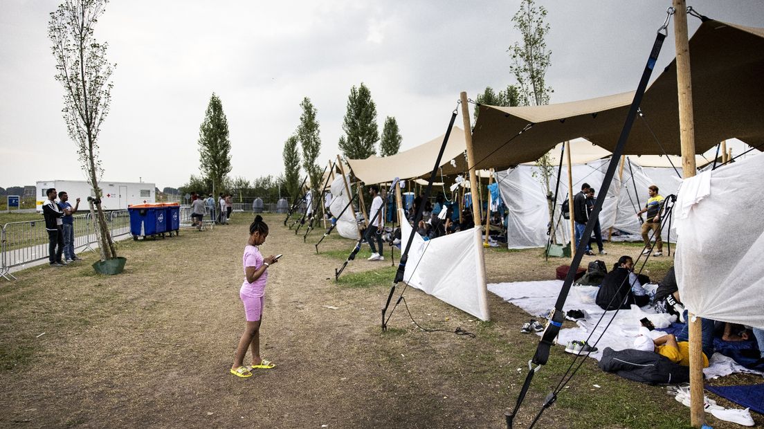 Mensen wachten bij het tentenkamp even buiten het aanmeldcentrum op 19 augustus