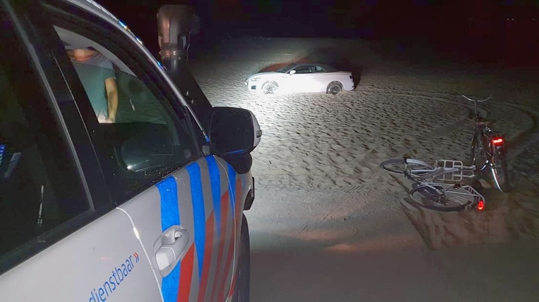 Strandvoertuig politie bij cabrio die vastzit in het mulle zand bij Renesse