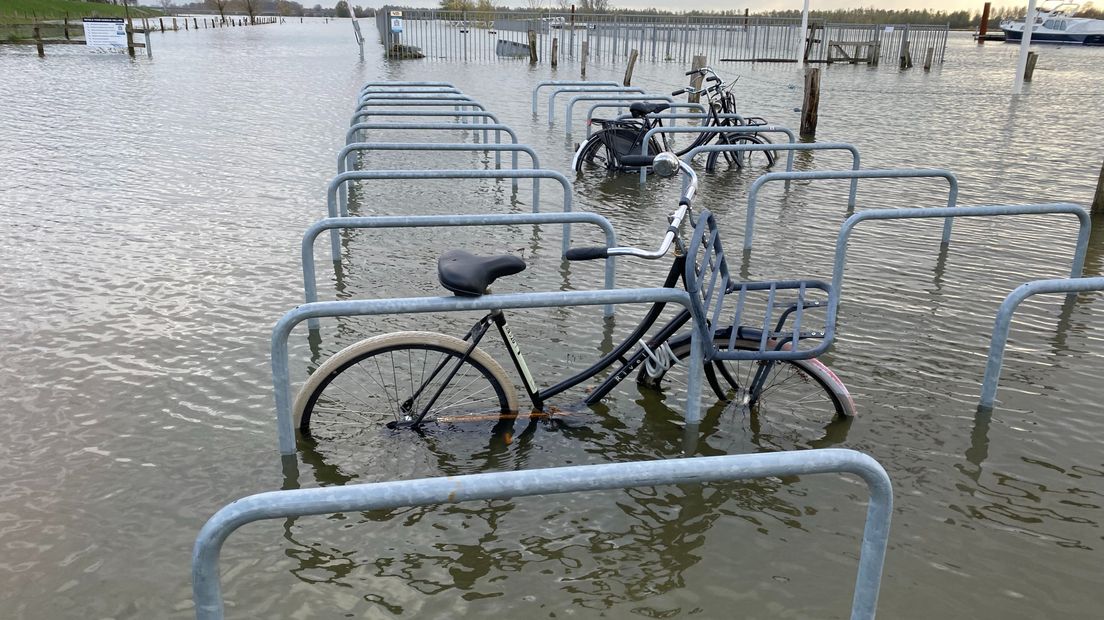 Fietsen bij de jachthaven in het water door de hoge waterstand in de IJssel
