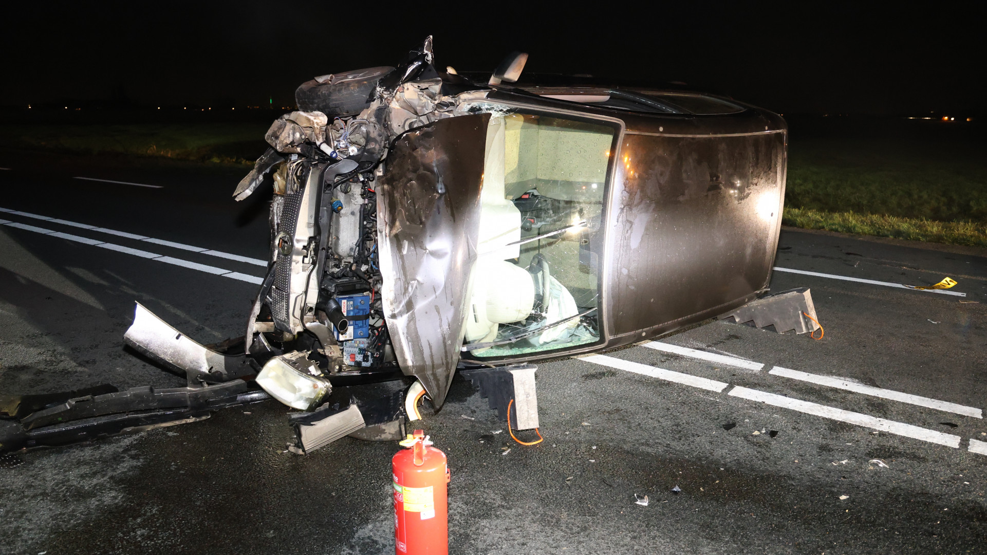 Auto op zijkant na botsing, weg helemaal dicht.