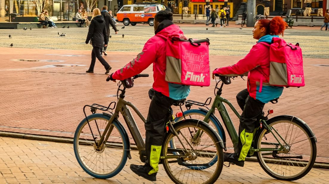 Twee bezorgers van flitsbezorger Flink fietsen over de Grote Markt