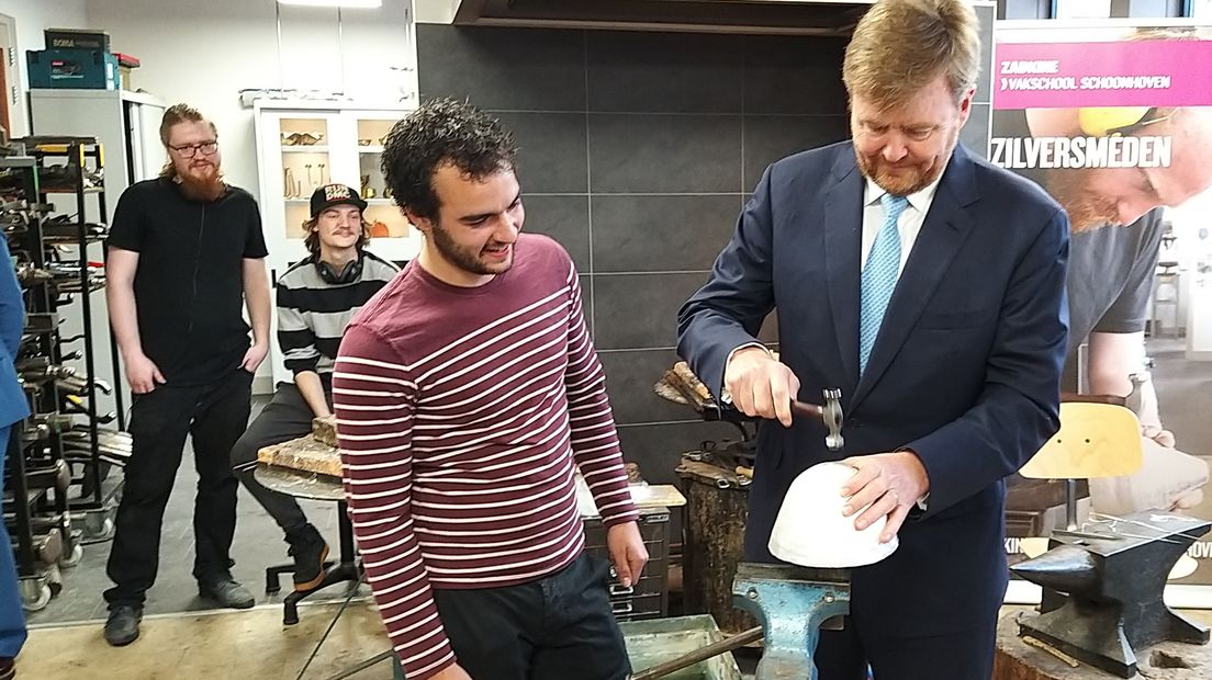 Koning Willem-Alexander bewerkt een zilveren schaal tijdens zijn bezoek aan Zadkine Vakschool Schoonhoven.
