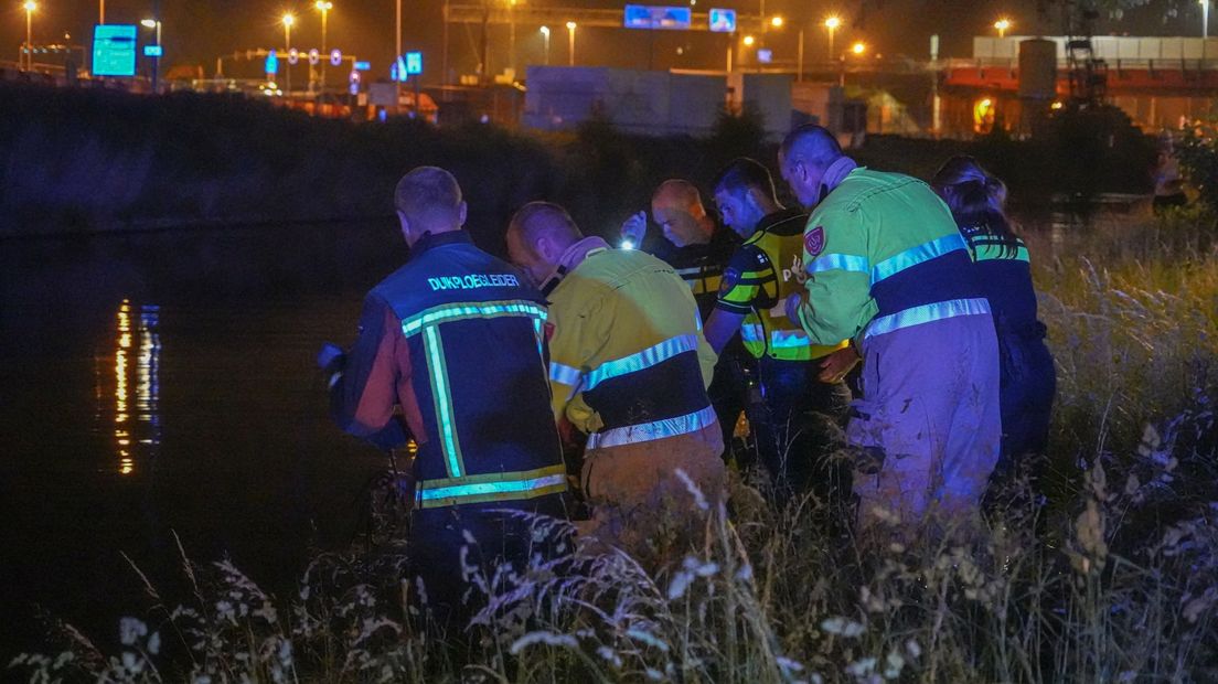 Brandweerlieden en politieagenten halen de vrouw uit het water van het Hoornsediep