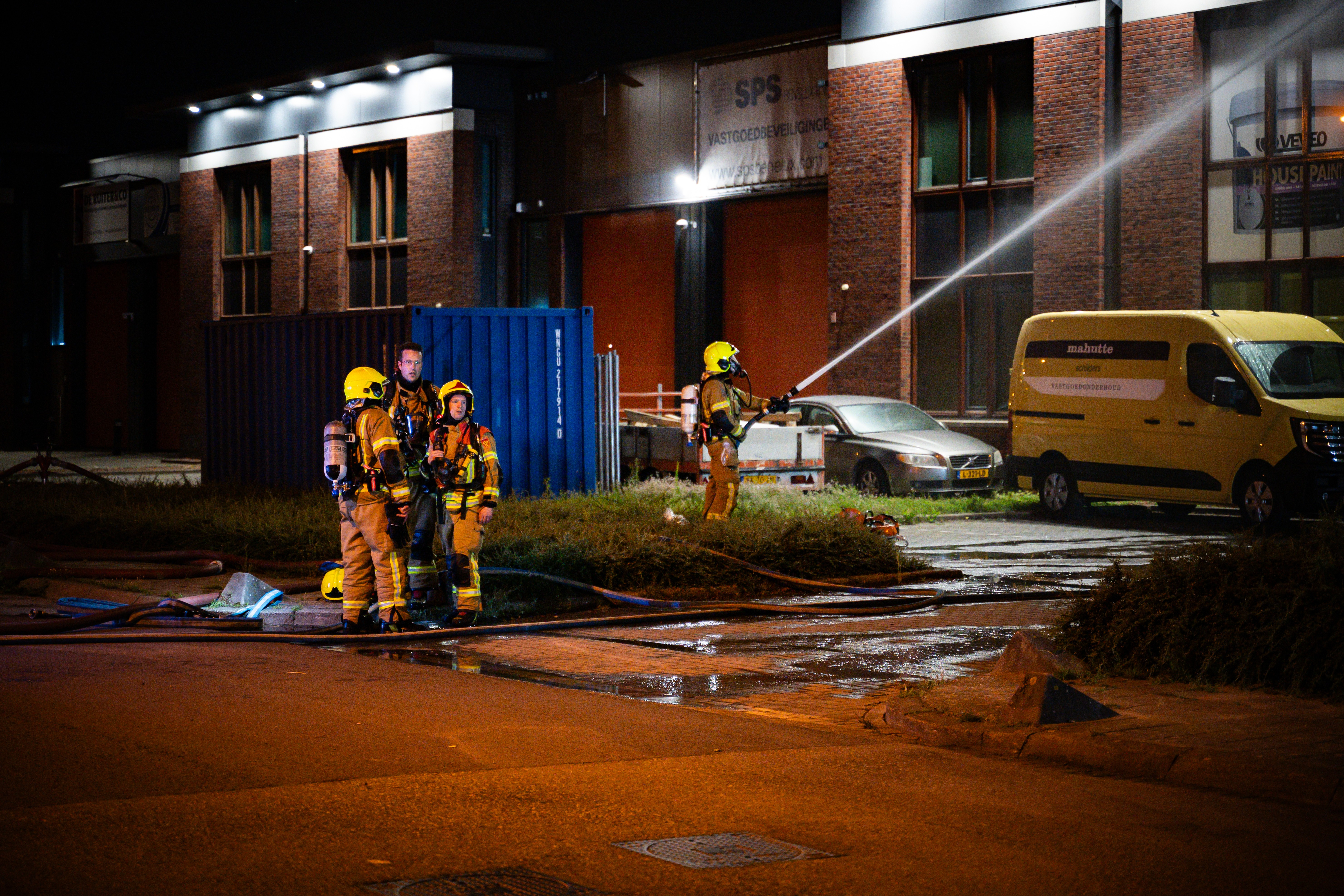 De brandweer is druk met het bestrijden van brand in het bedrijfspand.