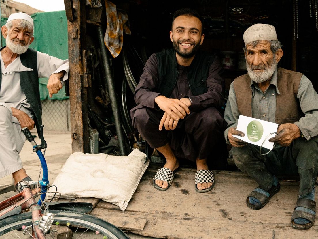 Faiz (midden) zag deze mannen een fiets repareren. De man rechts zorgt voor zes weeskinderen en zijn eigen kinderen. Faiz heeft hem geholpen