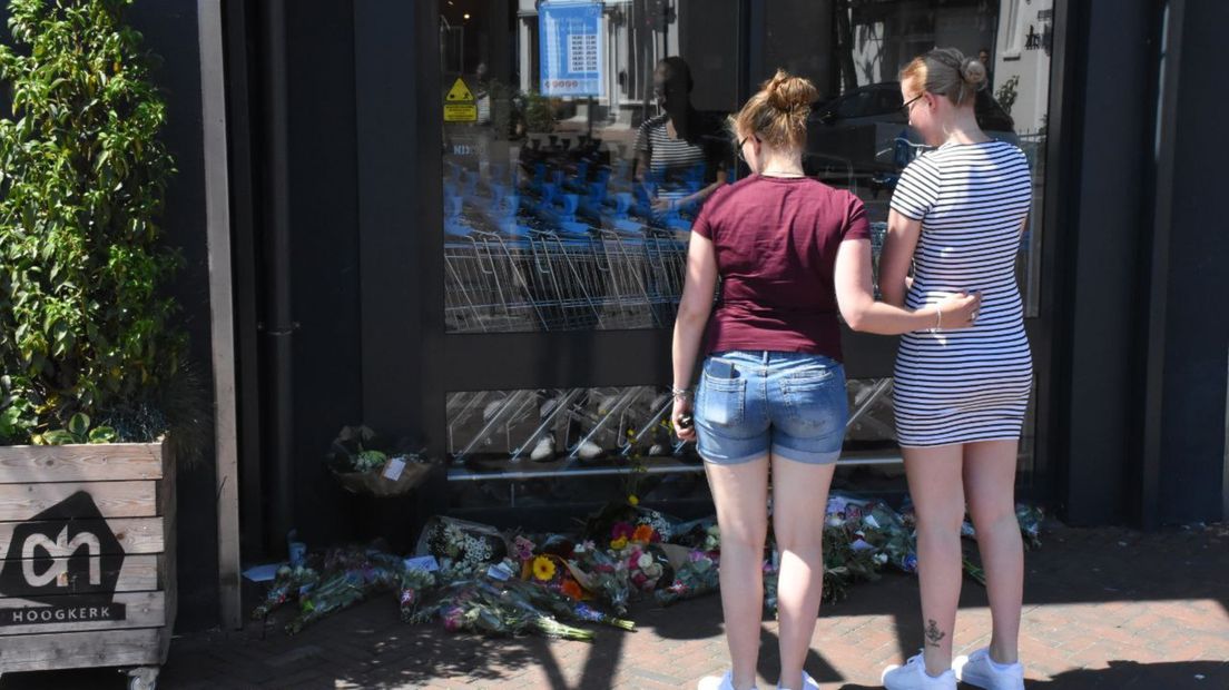 Omstanders kijken naar de bloemen die zijn neergelegd
