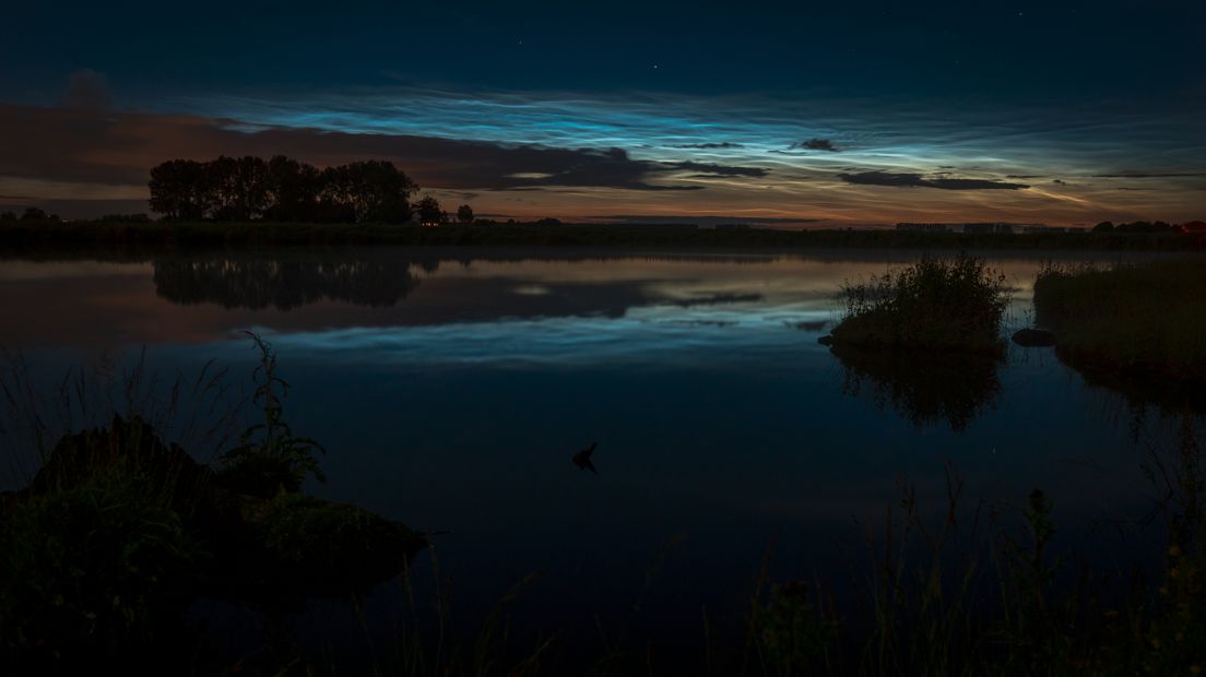 Lichtende nachtwolken boven de Otheense Kreek bij Terneuzen.