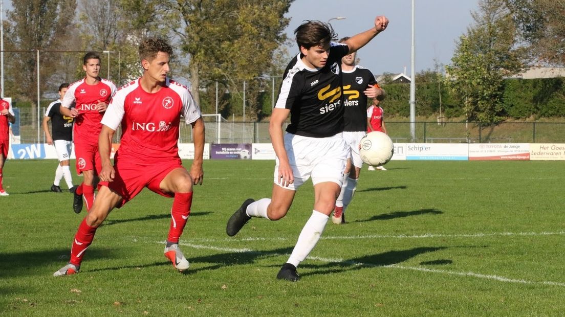 GOES-aanvaller Steve Schalkwijk (links) kijkt toe hoe Quick'20 de bal wegwerkt