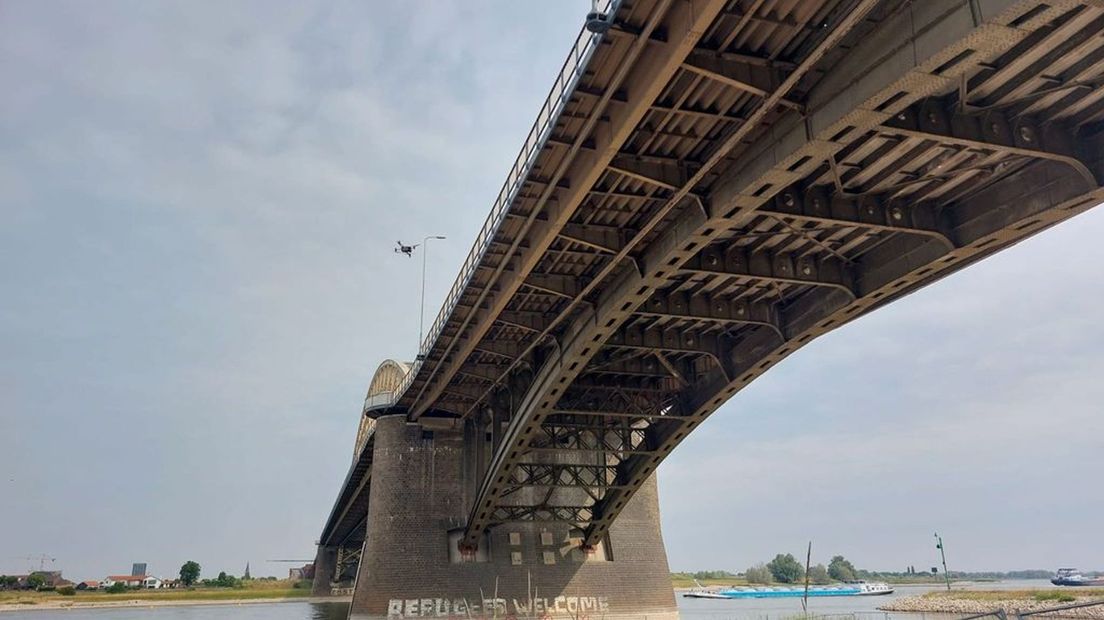 De drone maakt beelden bij de Waalbrug. Op het strand zijn de hekken te zien.