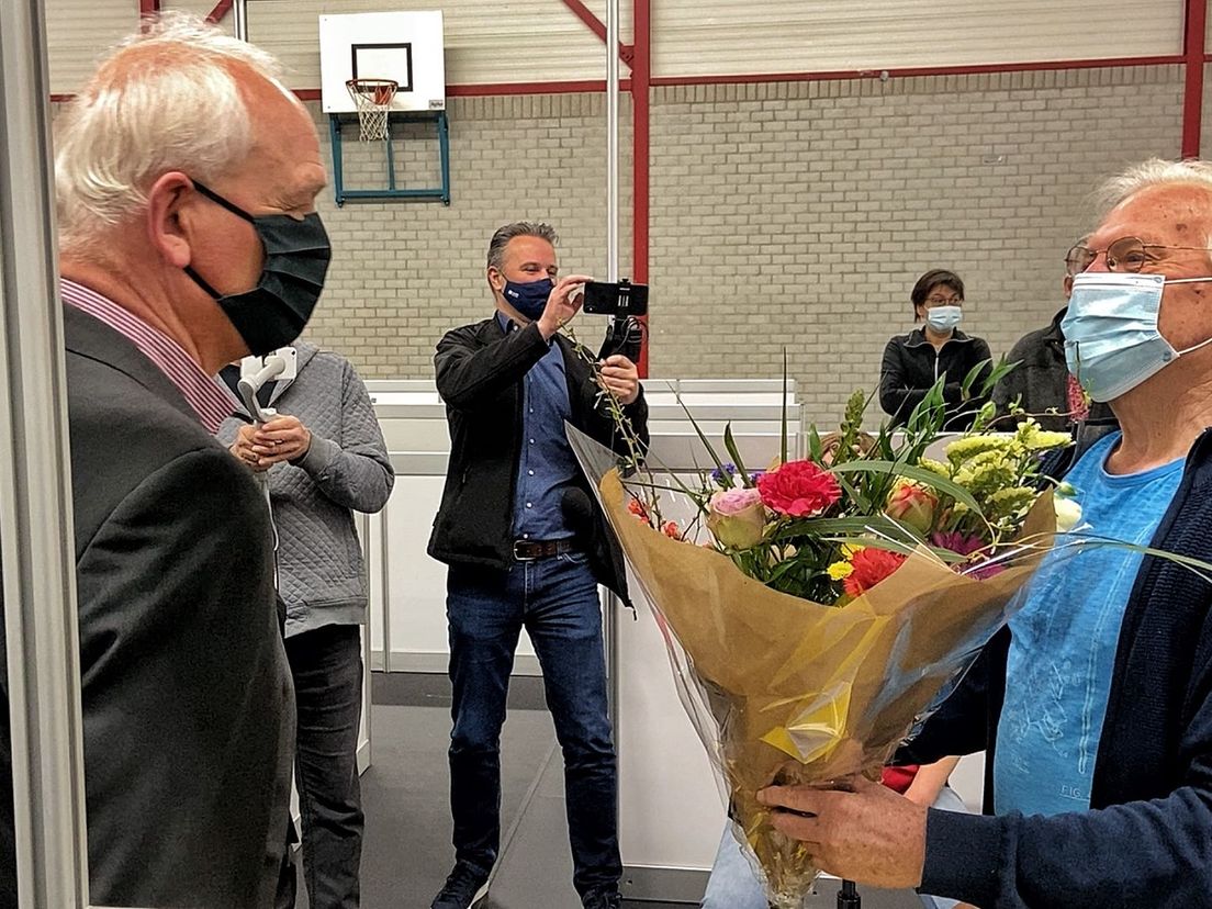 Henk Steenbergen ontvangt een bloemetje na zijn prik in Schiedam