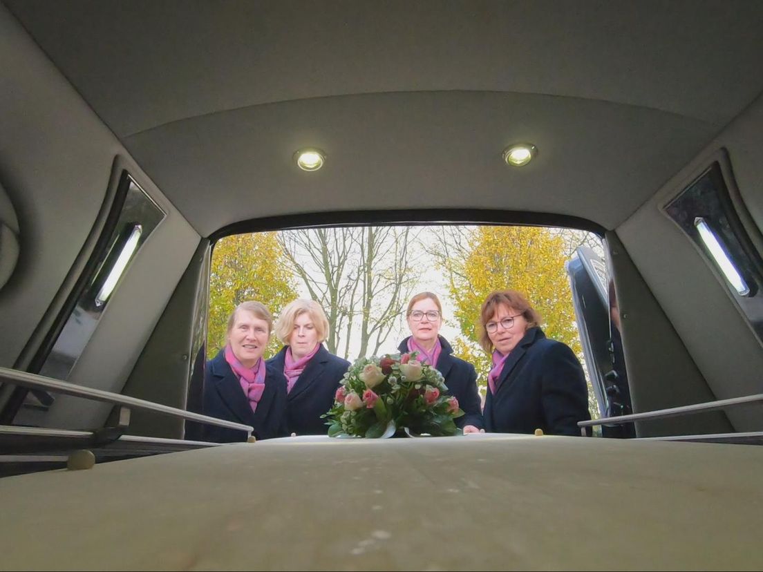 De dames halen de kist uit de lijkwagen