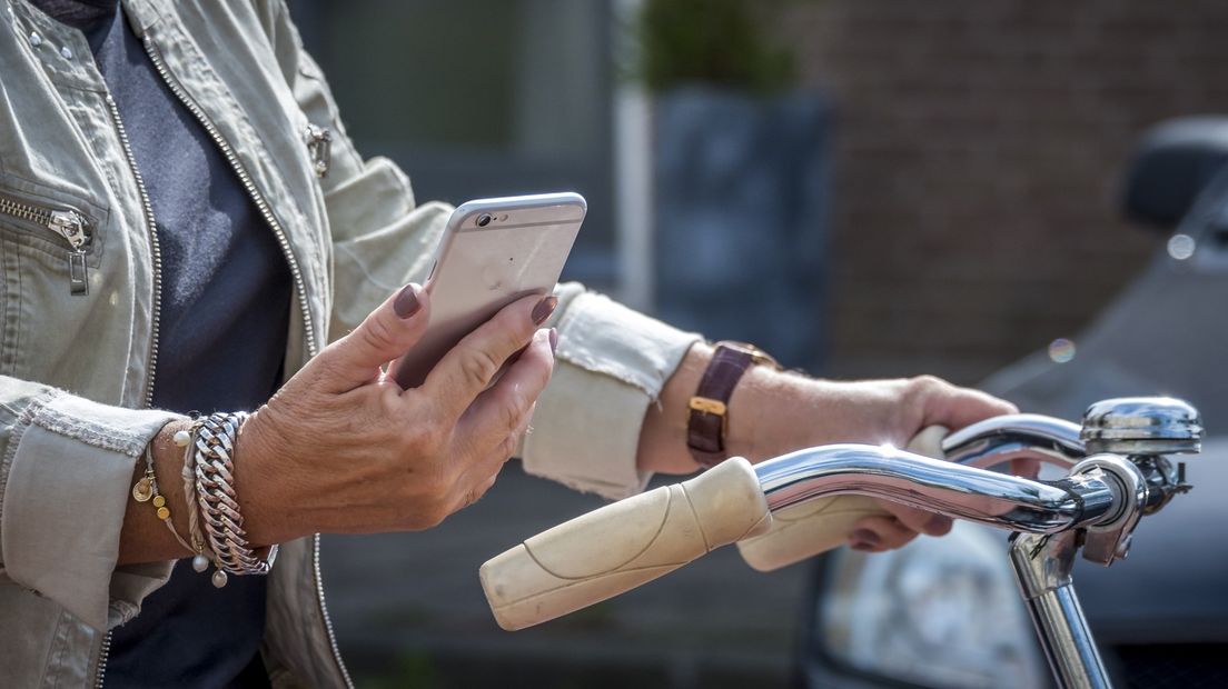 Een vrouw bekijkt haar telefoon tijdens het fietsen