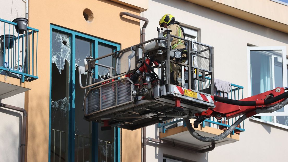 Een brandweerman bij de ingeslagen ramen