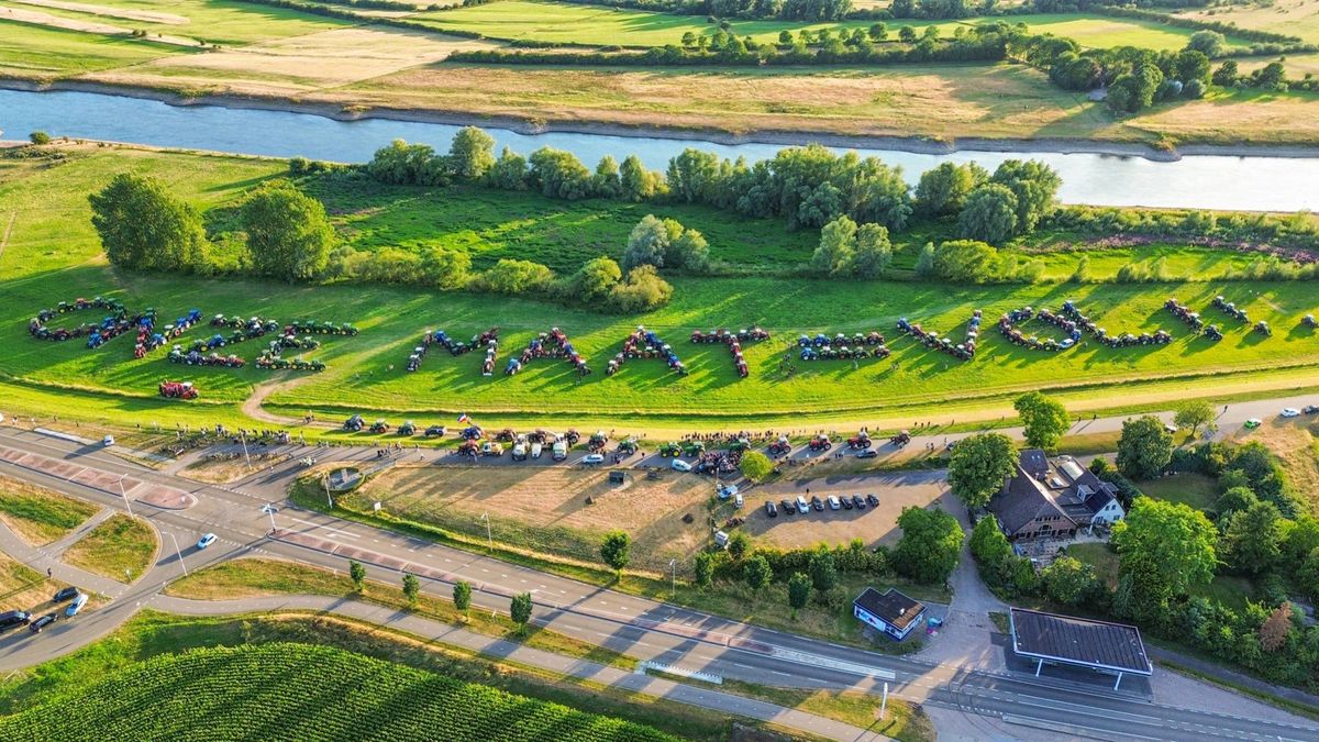 Boeren vormen met tractoren de tekst 'Onze maat = vol!!!'
