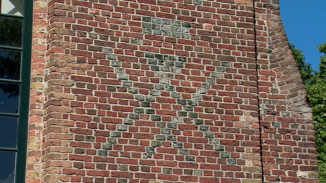 Het Andreaskruis in de vorm van een metselaarsteken op de kerkmuur in Grijpskerke