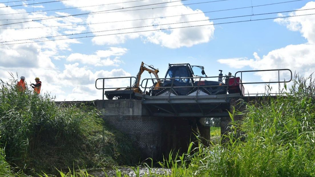 Maaitrekker omgevallen naast het spoor