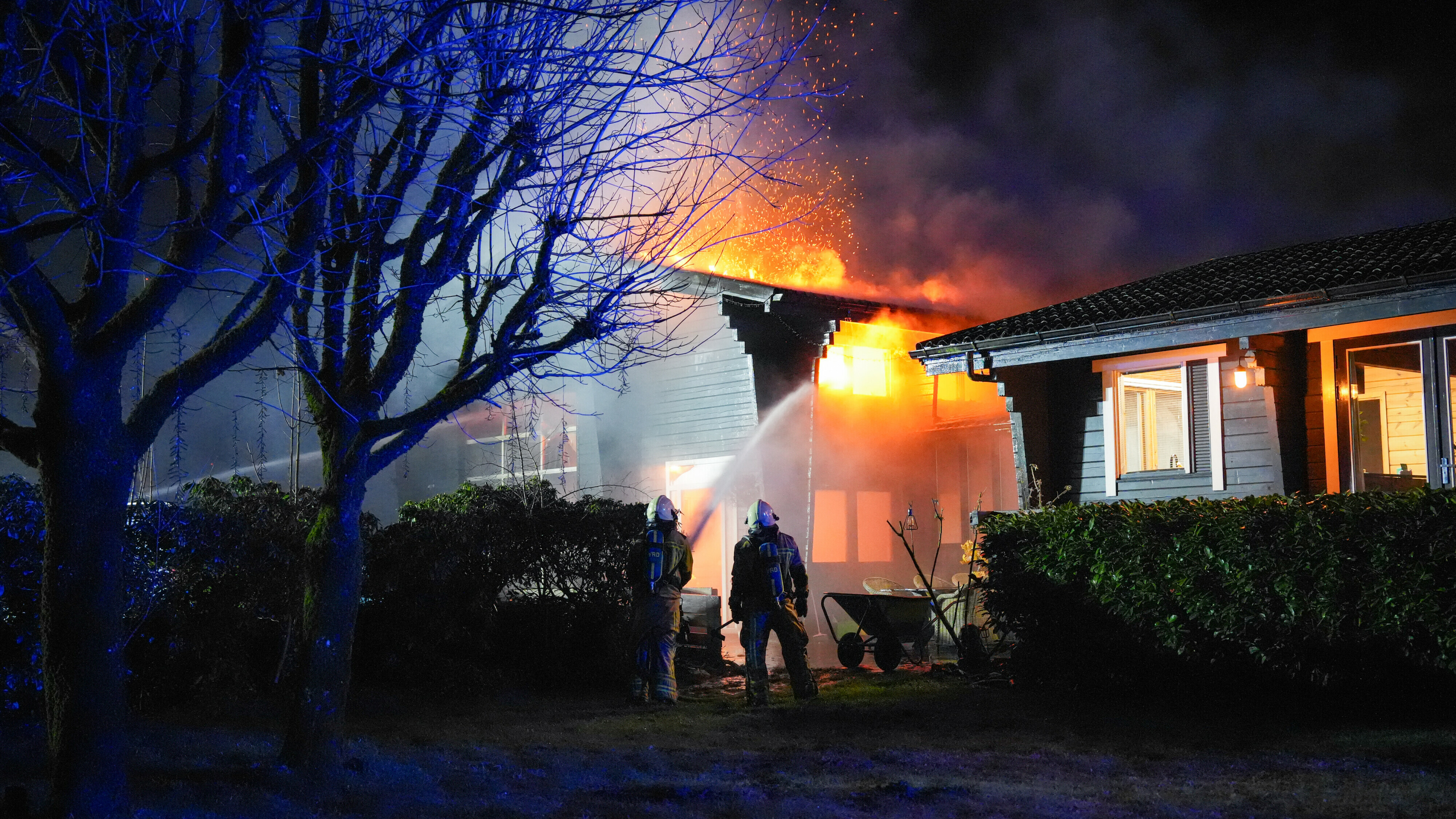 De brand bij het autobedrijf dreigt over te slaan naar een huis