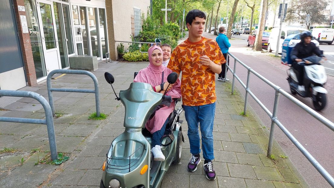 Redwan wandelt met zijn moeder naast haar scootmobiel