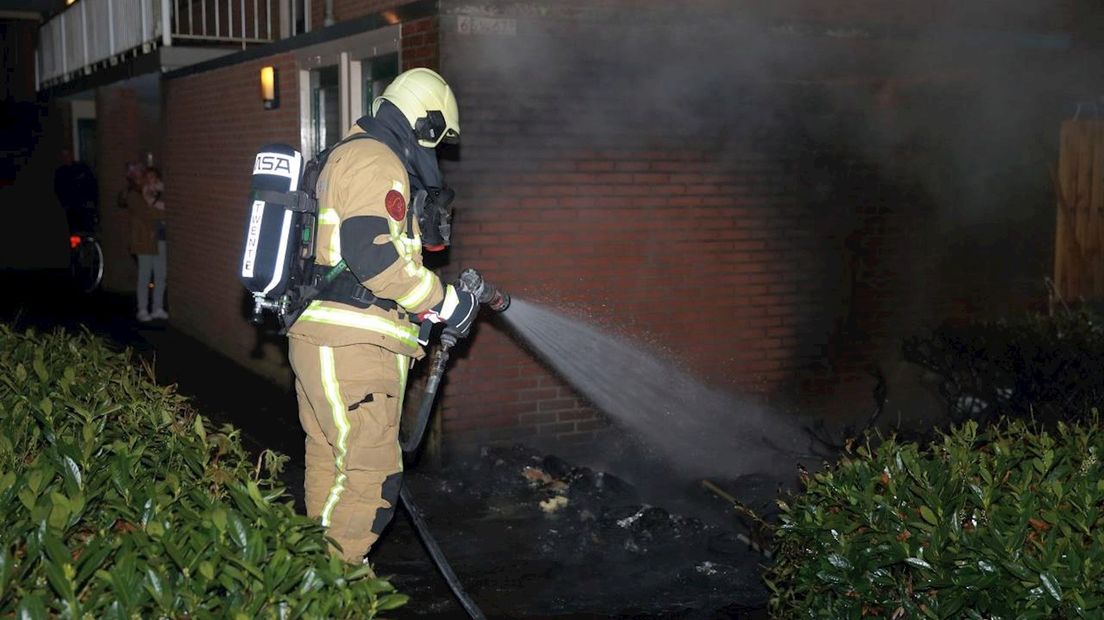 Brandweerlieden blussen de containerbrand