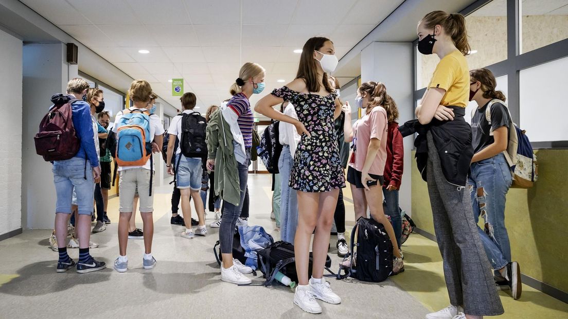 Leerlingen van de middelbare school dragen op de gang een mondkapje