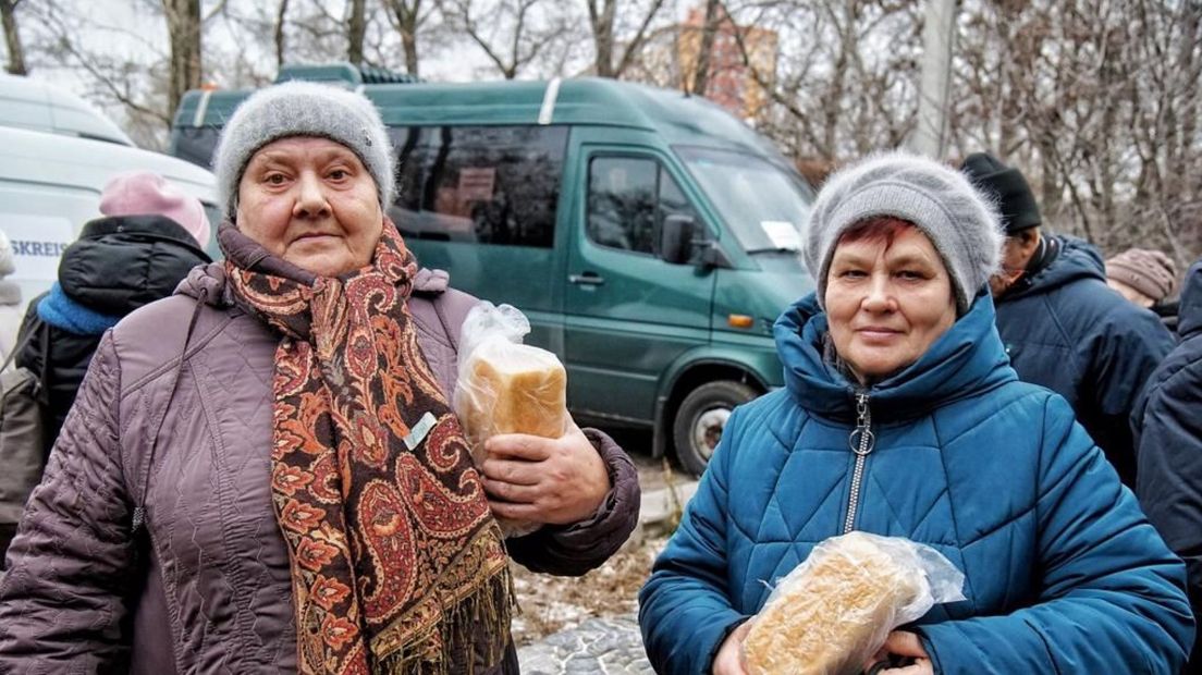 Twee Oekraïense vrouwen nemen een brood in ontvangst