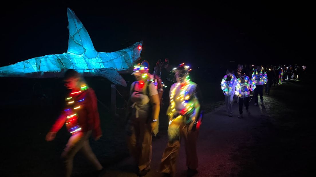 Mensen lopen langs een lichtgevende haai met geluiden uit de bekende blockbuster Jaws