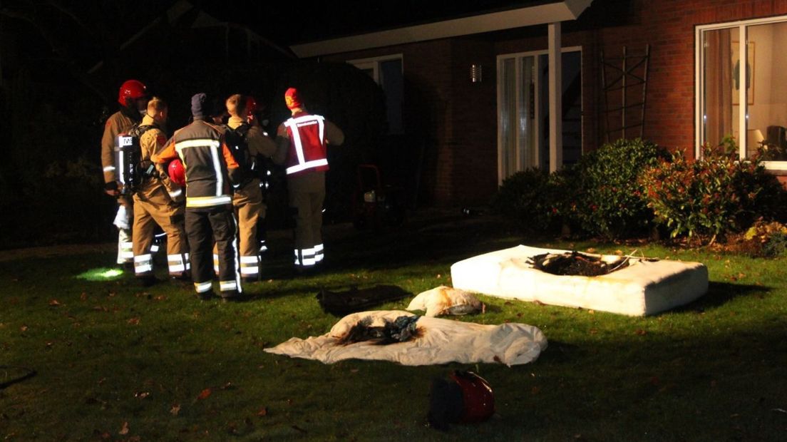 Brandweerlieden in overleg na het blussen van de matras en de deken