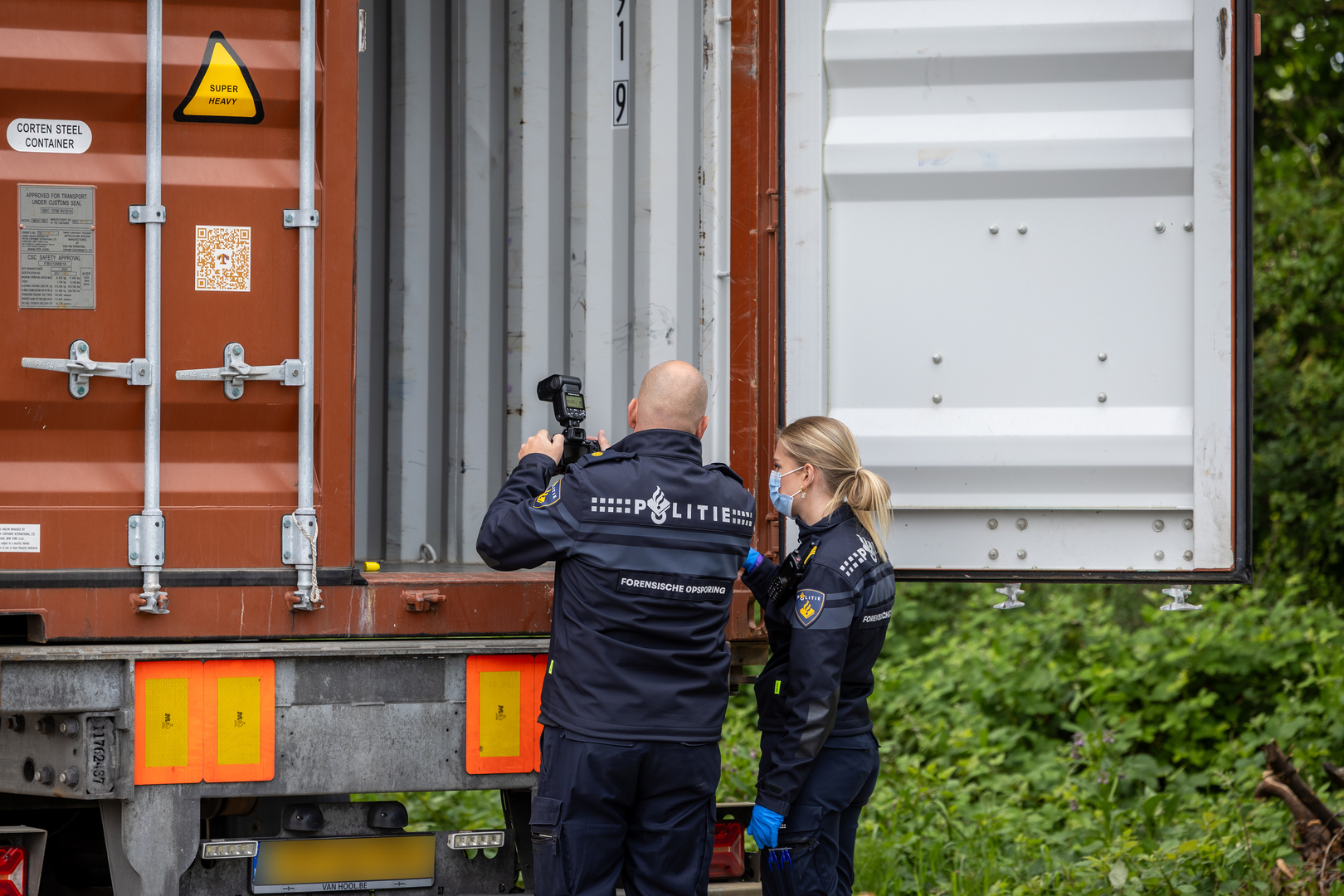De politie doet onderzoek bij de leeggeroofde container.