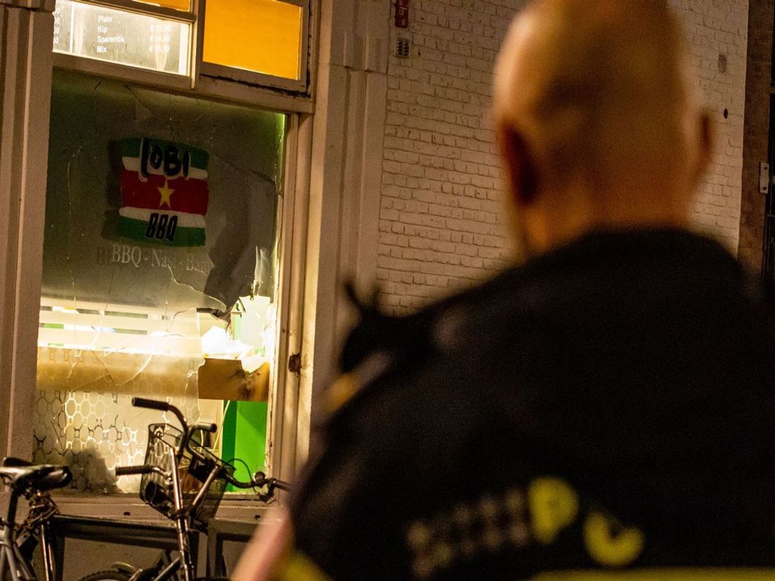 Een agent bekijkt de schade aan het pand van Lobi BBQ in Rotterdam - MediaTV | Foto: